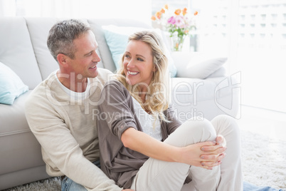 Happy casual couple sitting on rug