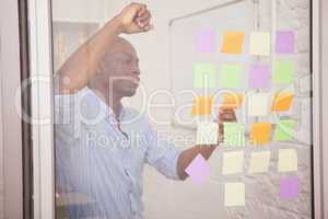 Thoughtful businessman looking at sticky notes on window