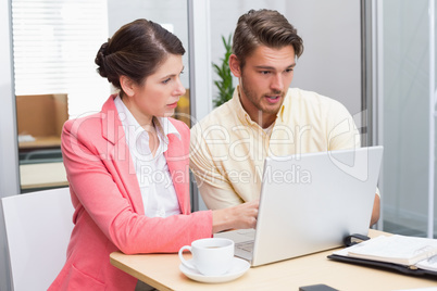 Focused business people working together on laptop