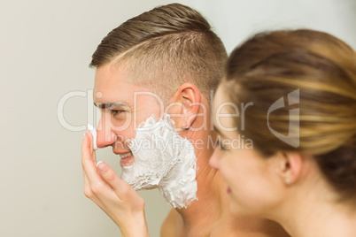 Woman putting shaving foam on boyfriends face