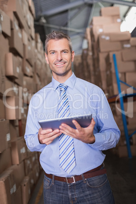 Manager using digital tablet in warehouse