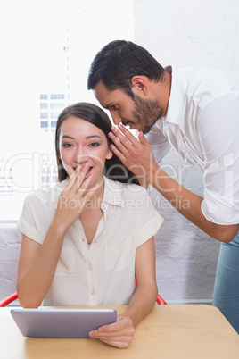 Man whispering into female friends ear