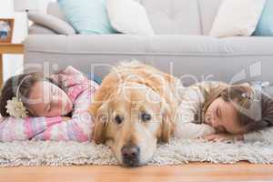 Sisters napping on rug with golden retriever