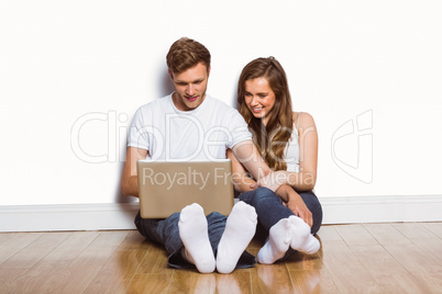 Young couple using laptop on floor