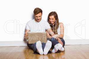 Young couple using laptop on floor