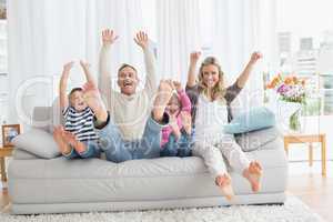 Family sitting on a couch and raising arms