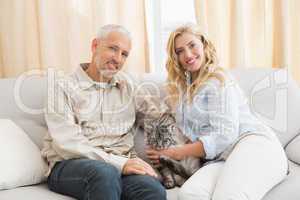Happy couple with pet cat on sofa
