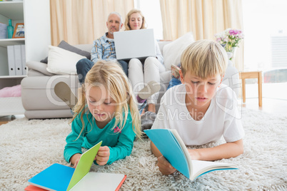 Siblings reading books on the floor