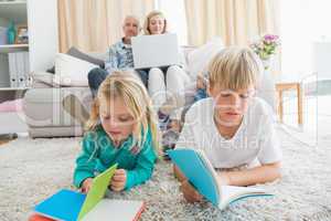 Siblings reading books on the floor