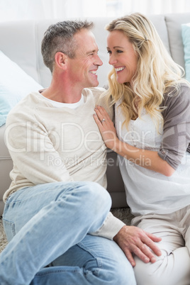 Happy casual couple sitting on rug