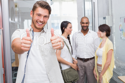 Man giving thumbs up at camera in front of his colleagues