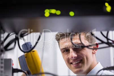 Smiling technician using digital cable analyzer on server
