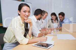 Businesswoman smiling at camera with team behind her