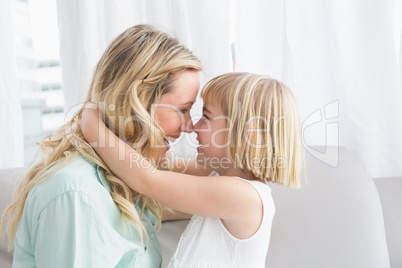 Mother and daughter rubbing noses on sofa