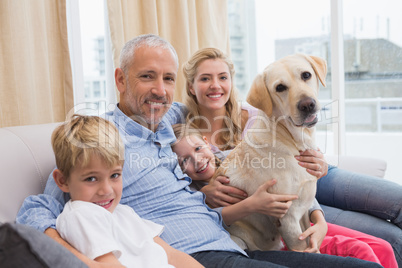 Parents and their children on sofa with labrador