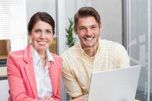 Business people working together on laptop and smiling