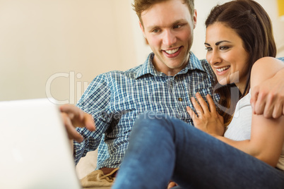 Happy young couple relaxing on the couch with laptop