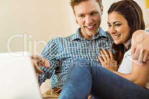 Happy young couple relaxing on the couch with laptop