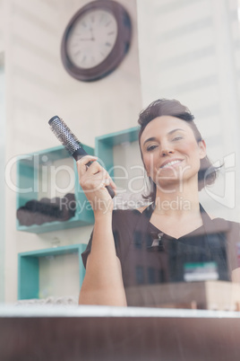 Smiling hairdresser holding hair brush