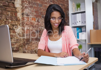 Woman writing notes with laptop