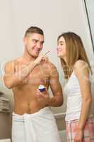 Handsome man putting cream on girlfriends nose