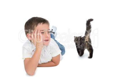 Cute boy looking at grey kitten lying on floor