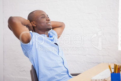 Businessman sitting with hands behind head at desk