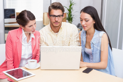 Business team using laptop and having coffee