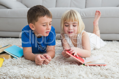 Siblings laying on the floor reading storybook