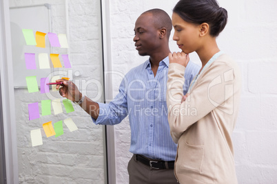 Creative business team looking at sticky notes on window