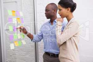 Creative business team looking at sticky notes on window