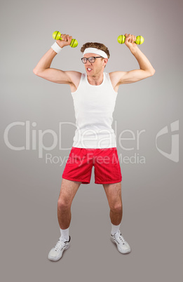 Geeky hipster posing in sportswear with dumbbells