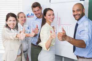 Smiling business team gesturing thumbs up in meeting
