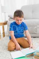 Little boy sitting on the floor reading storybook
