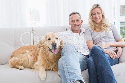 Cute couple relaxing together on the couch with their dog