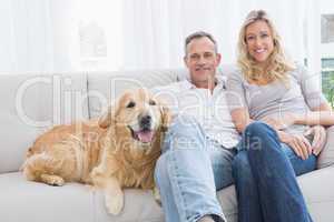 Cute couple relaxing together on the couch with their dog