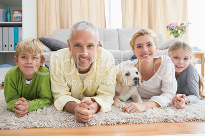 Happy parents with their children and puppy on floor