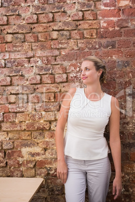 Thoughtful businesswoman against brick wall