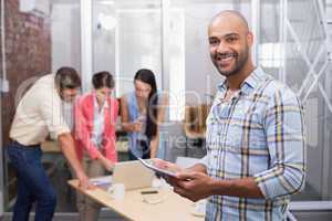 Smiling businessman holding tablet in front of his colleague