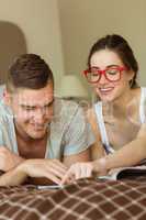 Cute couple reading newspaper in bed