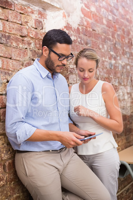 Business people text messaging against brick wall