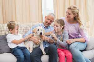 Parents with their children on sofa playing with puppy