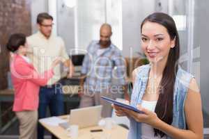 Smiling woman holding tablet in front of her colleague