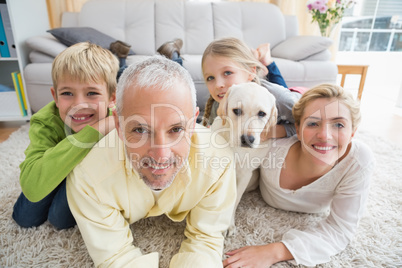 Happy parents with their children and puppy on floor