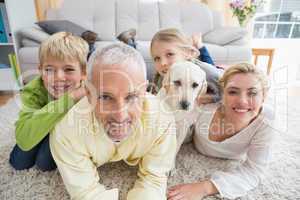Happy parents with their children and puppy on floor