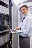 Portrait of a technician using laptop while analysing server
