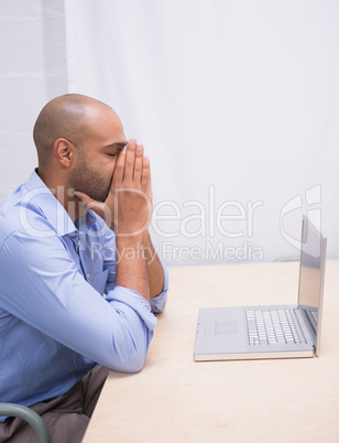 Businessman with head in hands by laptop at desk
