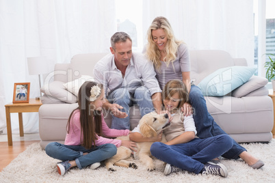 Smiling family with their pet yellow labrador on the rug