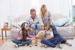 Smiling family with their pet yellow labrador on the rug