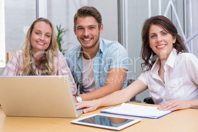 Smiling colleagues with laptop and digital tablet in meeting